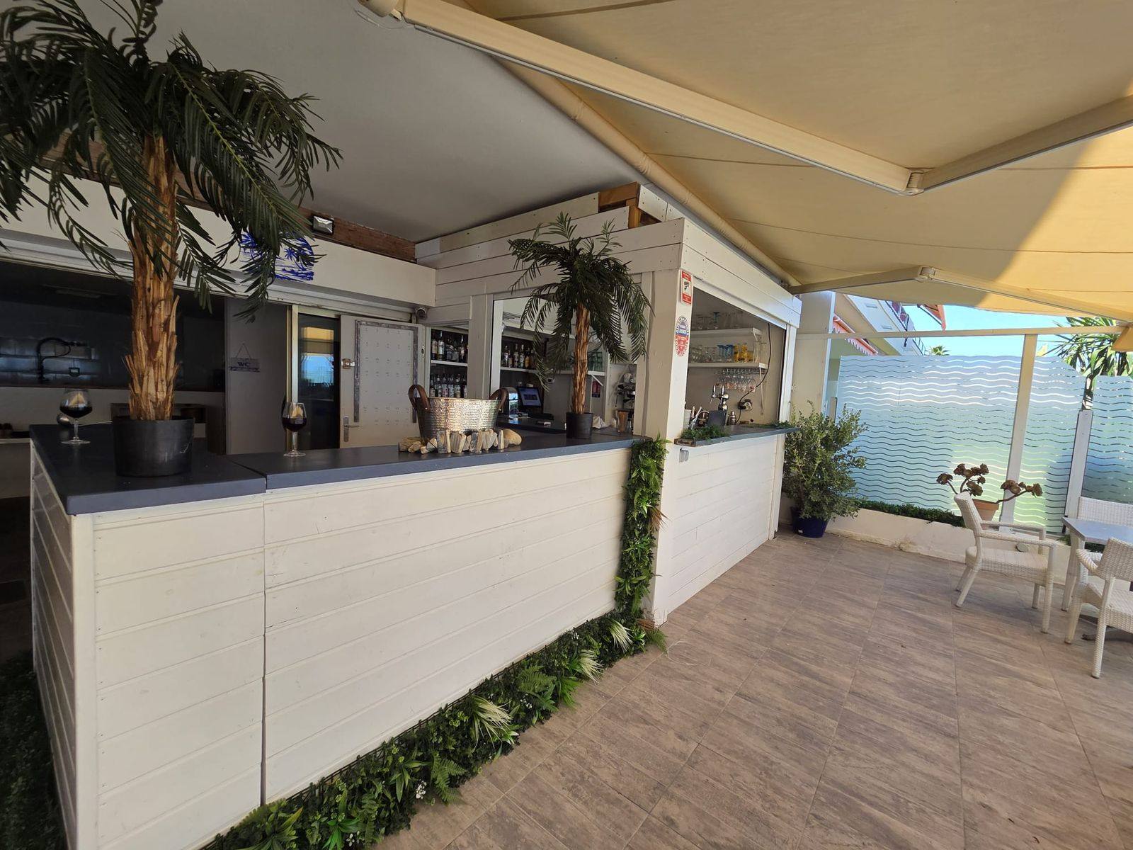 Le bar de L&rsquo;Indigo, comptoir en bois blanc et bouteilles alignées, ouvert sur la terrasse
